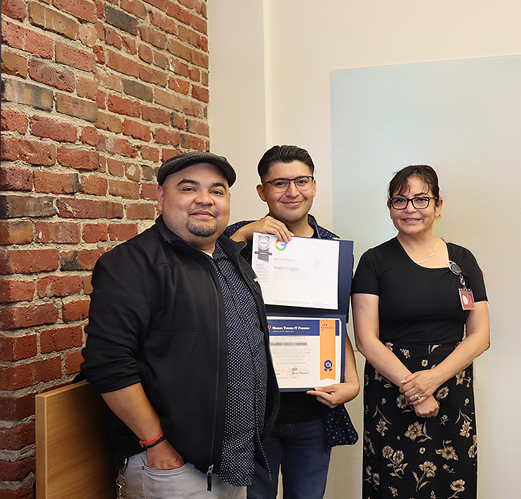 Two instructors next toa graduate holding a certificate.